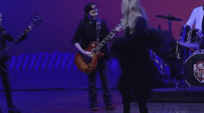 A Man Playing A Guitar And A Woman Singing On A Stage GIF