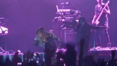 A Man Playing A Guitar And Another Man Playing A Keyboard Are On A Stage GIF