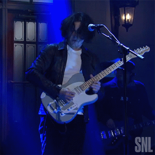 A Man Playing A Guitar And Singing Into A Microphone With Snl Written On The Bottom GIF