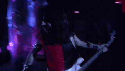A Man Playing A Guitar In A Dark Room GIF