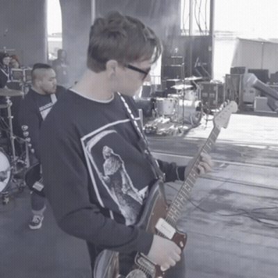 A Man Playing A Guitar In Front Of A Band GIF