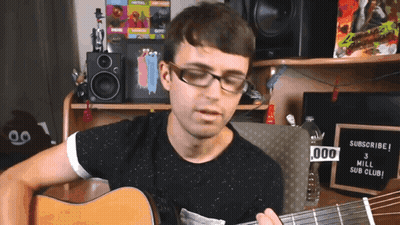 A Man Playing A Guitar In Front Of A Sign That Says " Subscribe " GIF