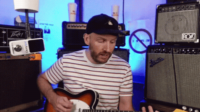 A Man Playing A Guitar In Front Of An Amp That Says Roz GIF