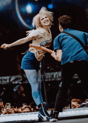 A Man Playing A Guitar Next To A Woman Dancing On Stage GIF