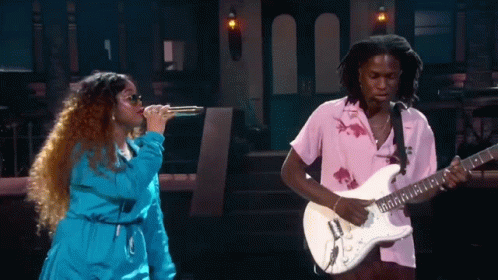 A Man Playing A Guitar Next To A Woman Singing GIF