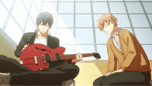 A Man Playing A Guitar Next To Another Man Sitting On The Floor GIF