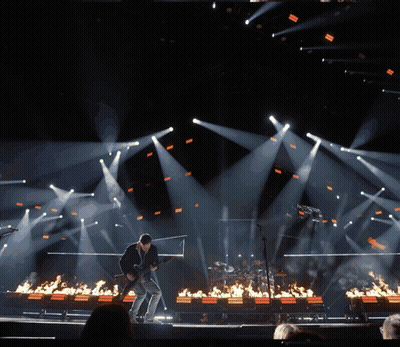 A Man Playing A Guitar On A Stage Surrounded By Fire GIF