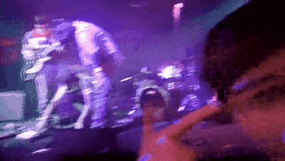 A Man Playing A Guitar On A Stage With Purple Lights GIF