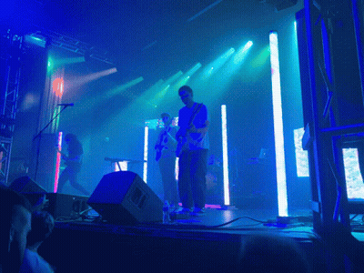 A Man Playing A Guitar On Stage With A Crowd Watching GIF