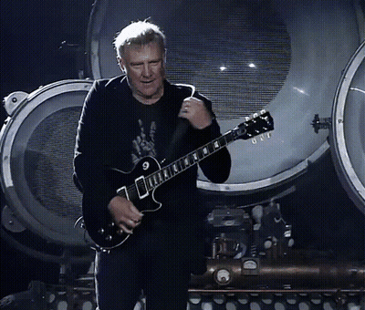 A Man Playing A Guitar With The Letter G On The Neck GIF