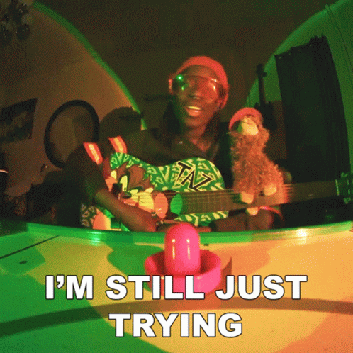 A Man Playing A Guitar With The Words I 'M Still Just Trying On The Bottom GIF