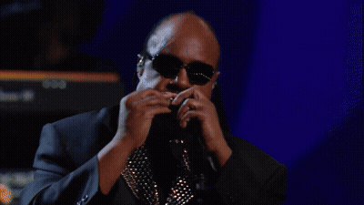 A Man Playing A Harmonica In Front Of A Keyboard That Says Yamaha GIF