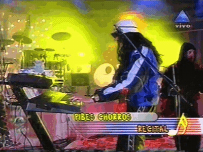A Man Playing A Keyboard In Front Of A Sign That Says " Pibes Charros Recital " GIF
