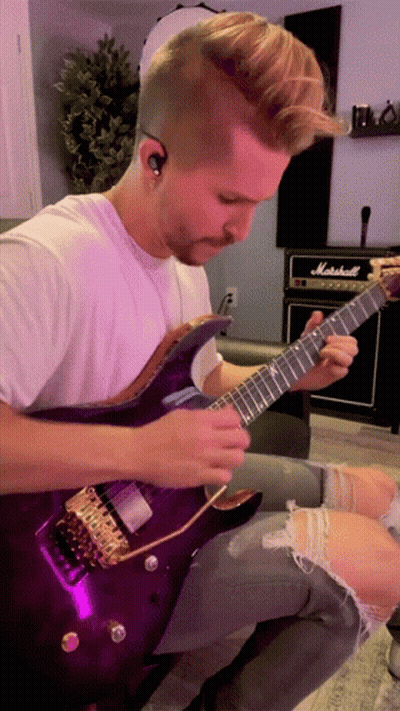 A Man Playing A Purple Guitar In Front Of A Marshall Amplifier GIF