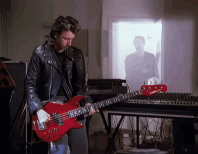 A Man Playing A Red Bass Guitar In Front Of A Yamaha Mixer GIF