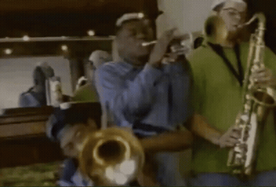 A Man Playing A Trumpet And Another Man Playing A Saxophone In Front Of A Mirror GIF