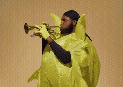 A Man Playing A Trumpet In A Yellow Outfit GIF