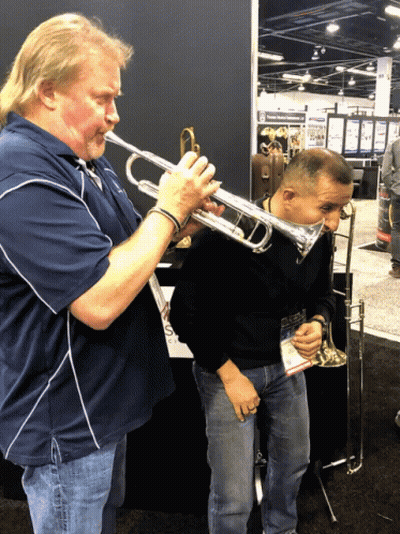 A Man Playing A Trumpet Next To Another Man GIF