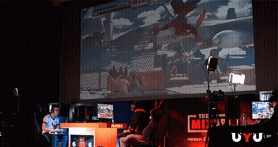 A Man Playing A Video Game On A Large Screen With A Sign That Says The Mix GIF