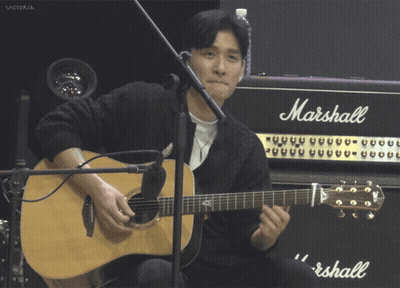 A Man Playing An Acoustic Guitar In Front Of A Marshall Amp GIF