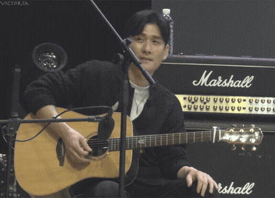 A Man Playing An Acoustic Guitar In Front Of A Marshall Amp GIF