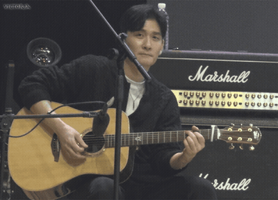 A Man Playing An Acoustic Guitar In Front Of A Marshall Amplifier GIF