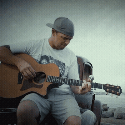 A Man Playing An Acoustic Guitar With A Taylor Logo On It GIF
