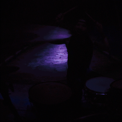 A Man Playing Drums In A Dark Room GIF