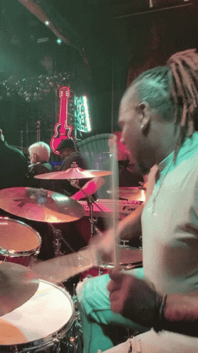 A Man Playing Drums In Front Of A Guitar That Says ' Elvis ' On It GIF