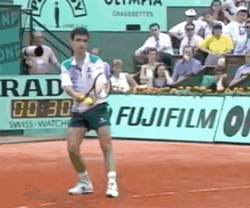 A Man Playing Tennis In Front Of A Fujifilm Banner GIF
