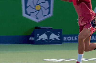 A Man Playing Tennis In Front Of A Red Bull Sign GIF