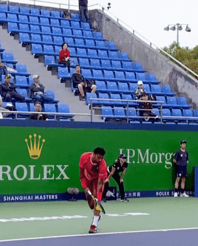 A Man Playing Tennis On A Court With A Rolex Ad Behind Him GIF