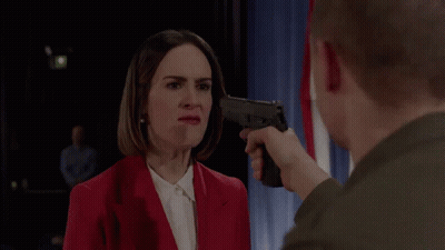 A Man Pointing A Gun At A Woman In A Red Jacket GIF