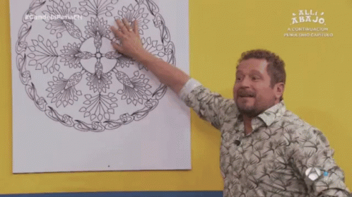 A Man Pointing At A Drawing On A Yellow Wall With The Words All Abajo On The Bottom GIF