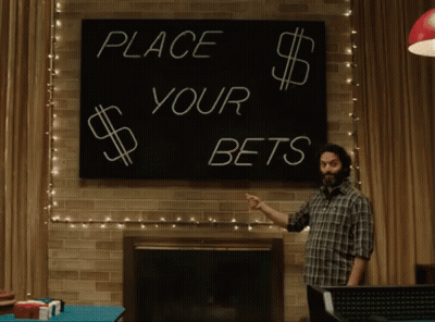 A Man Pointing At A Sign That Says Place Your Bets GIF