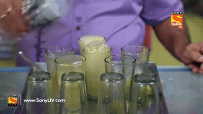A Man Pouring A Drink Into A Tray Of Empty Glasses With A Sony Logo On The Bottom GIF