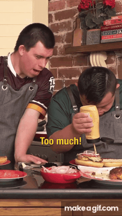 A Man Pouring Mustard On A Hot Dog While Another Man Looks On And Says Too Much GIF