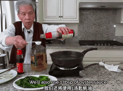 A Man Pouring Oyster Sauce Into A Frying Pan In A Kitchen GIF