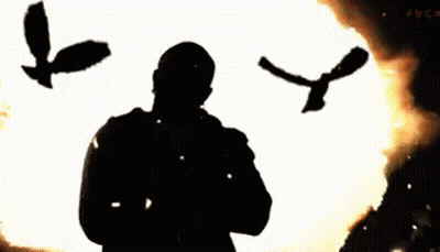 A Man Praying In Front Of A Fire With Birds Flying Around Him GIF