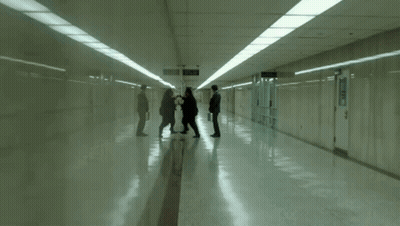 A Man Pushing Another Man In A Hallway With The Words Uuuu Written On The Floor GIF
