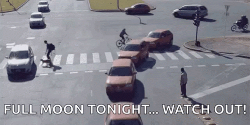 A Man Riding A Bike In A Busy Intersection With The Words Full Moon Tonight Watch Out Below Him GIF