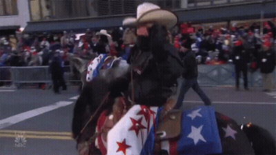 A Man Riding A Horse In A Parade With A Merry Thanksgiving Star GIF