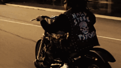 A Man Riding A Motorcycle With A Jacket That Says Psycho On It GIF