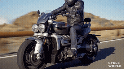 A Man Riding A Triumph Motorcycle On The Road GIF