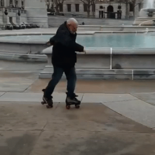 A Man Rollerblading In Front Of A Fountain In A Park GIF