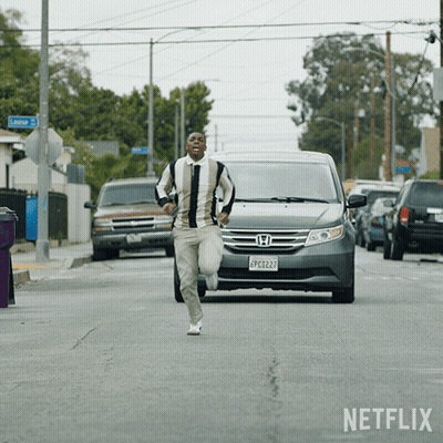A Man Running Down A Street In Front Of A Netflix Ad GIF