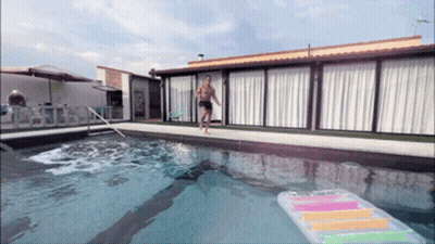 A Man Runs Into A Swimming Pool With A Raft In The Water GIF
