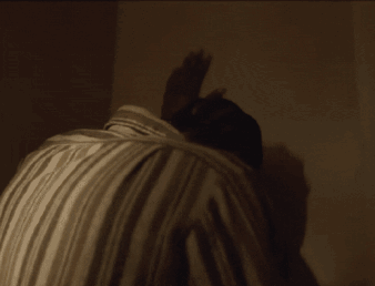 A Man 'S Back Is Shown In A Dark Room GIF