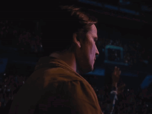 A Man 'S Face Is Shown In A Dark Room GIF