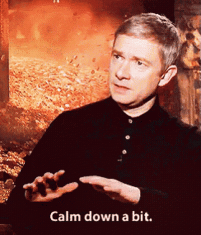 A Man Says Calm Down A Bit In Front Of A Fire Background GIF
